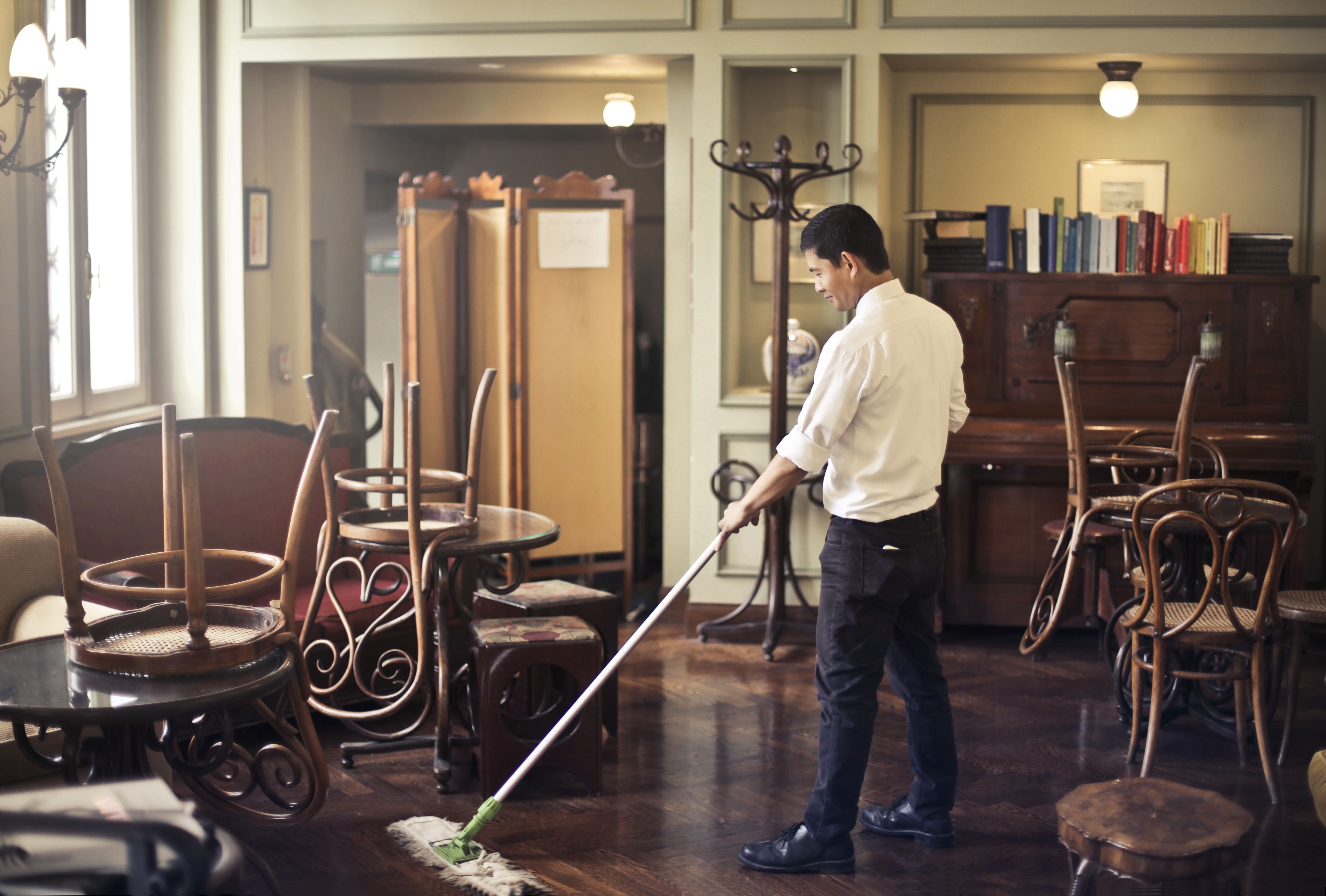 Worker mopping the floor of a closed restaurant.