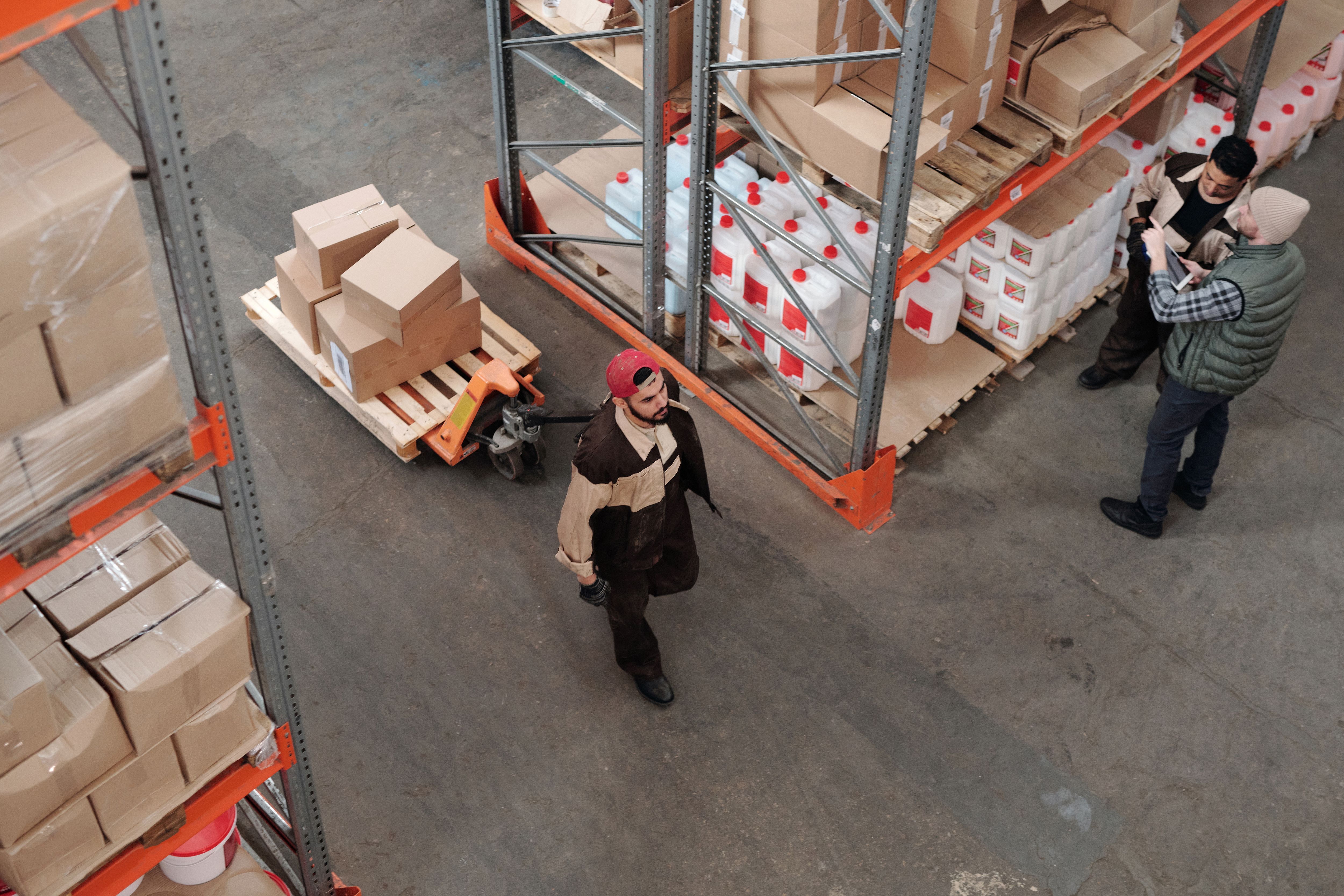 Warehouse workers coordinating around palletized inventory.