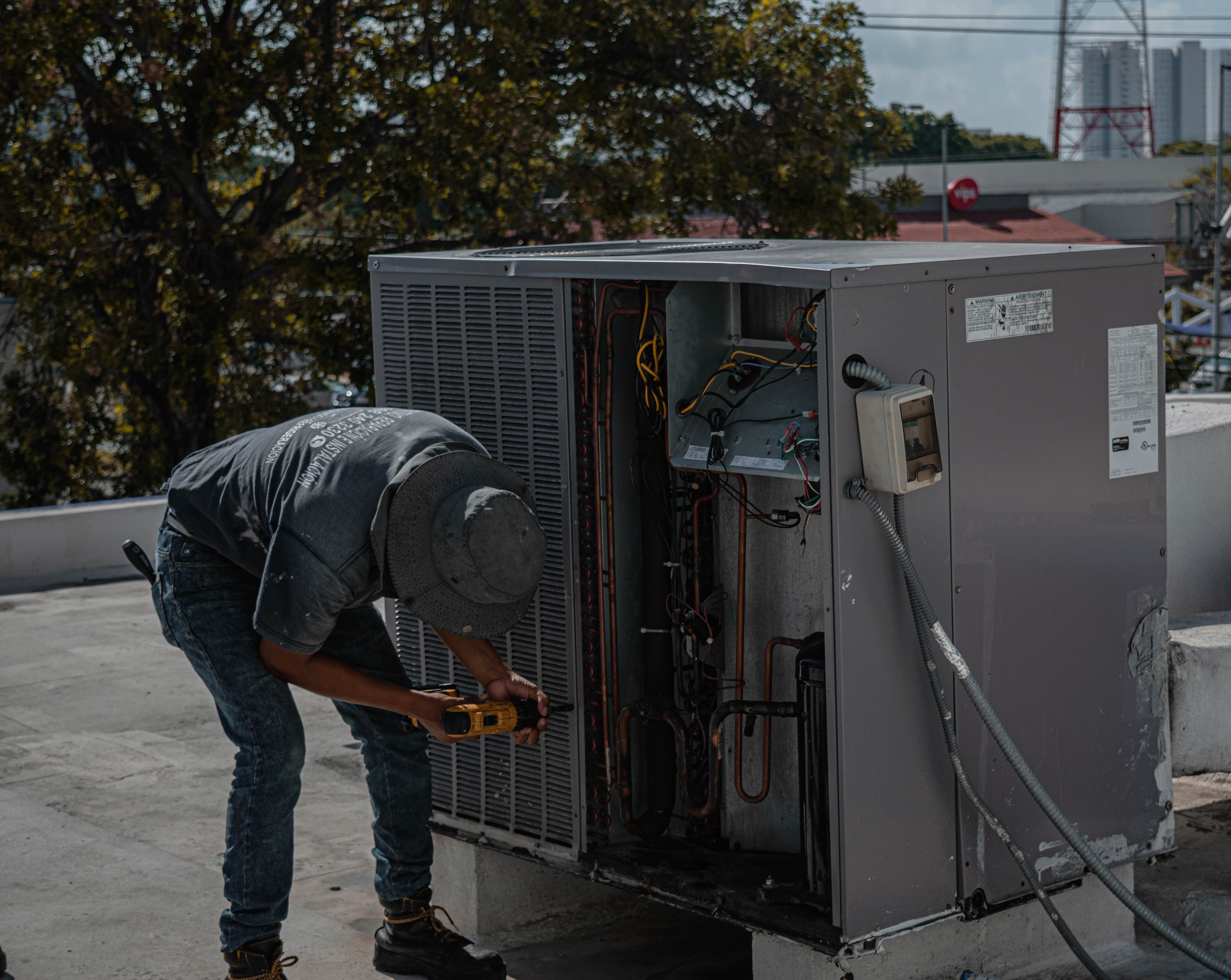 Technician repairing an open rooftop air-conditioning unit.