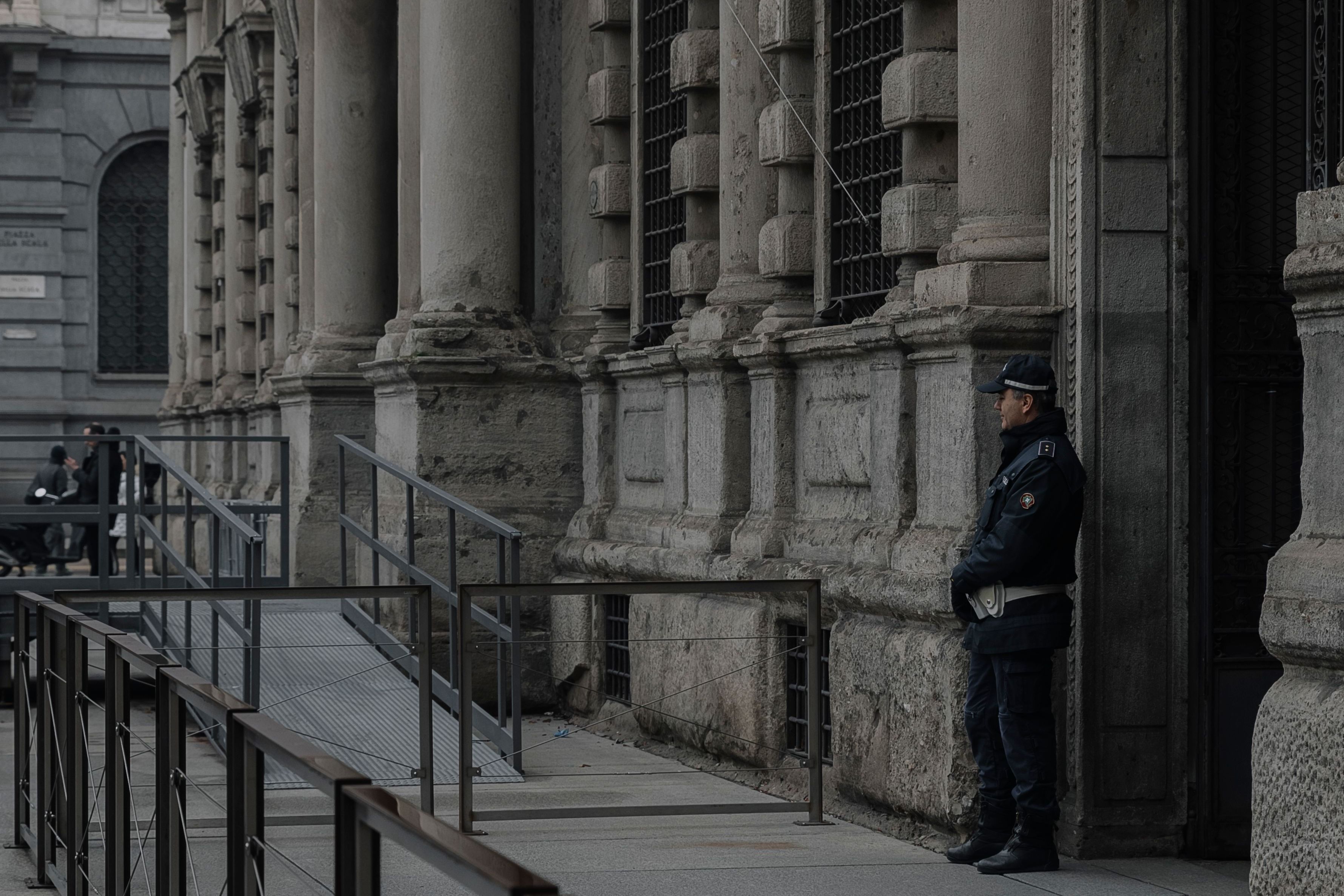 Uniformed security guard monitoring the entrance of a commercial building.