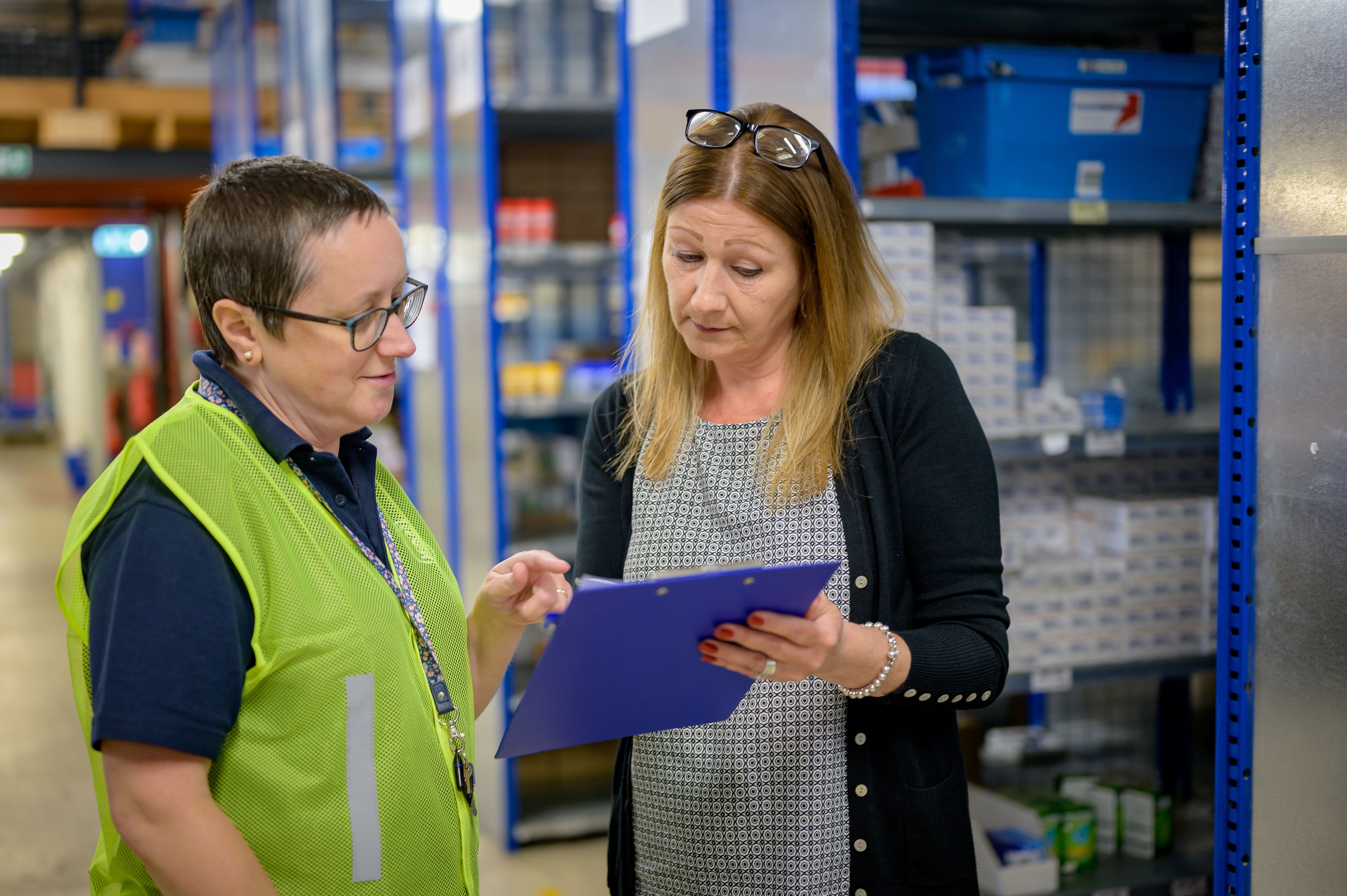 Two workers reviewing a clipboard in a warehouse.
